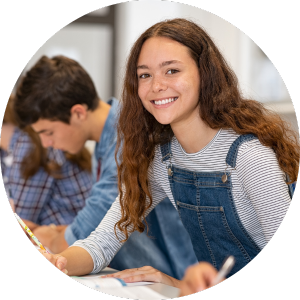 enthusiastic teen girl student at desk with pencil and notebook